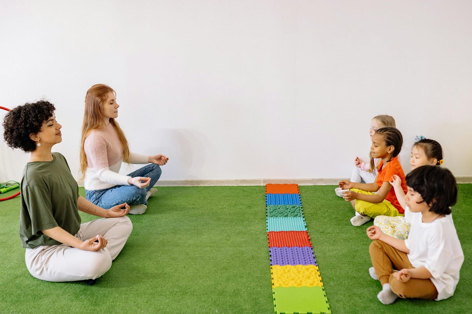 Kids and teachers in a preschool yoga session practicing mindfulness indoors.